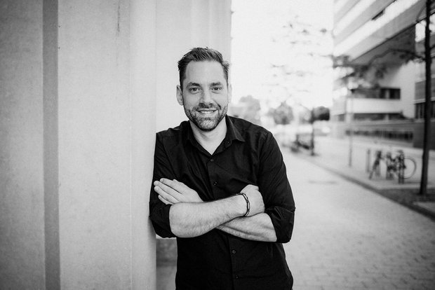 Moritz Kühnel, SEO-Berater, lehnt an der Wand, schwarz-weiß Bild,